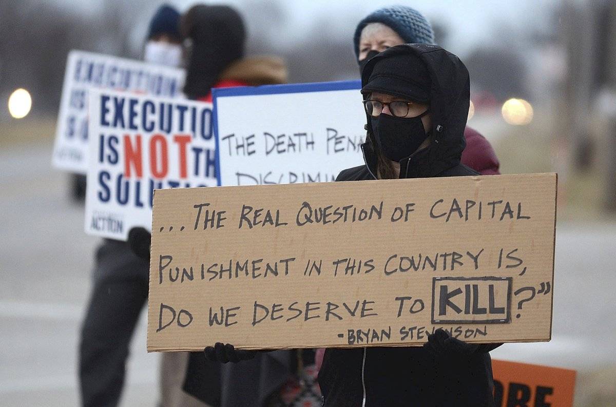 Christina Bollo de Urbana, Illinois, sostiene un cartel mientras protesta por la ejecución de Corey Johnson, cerca del Complejo Correccional Federal