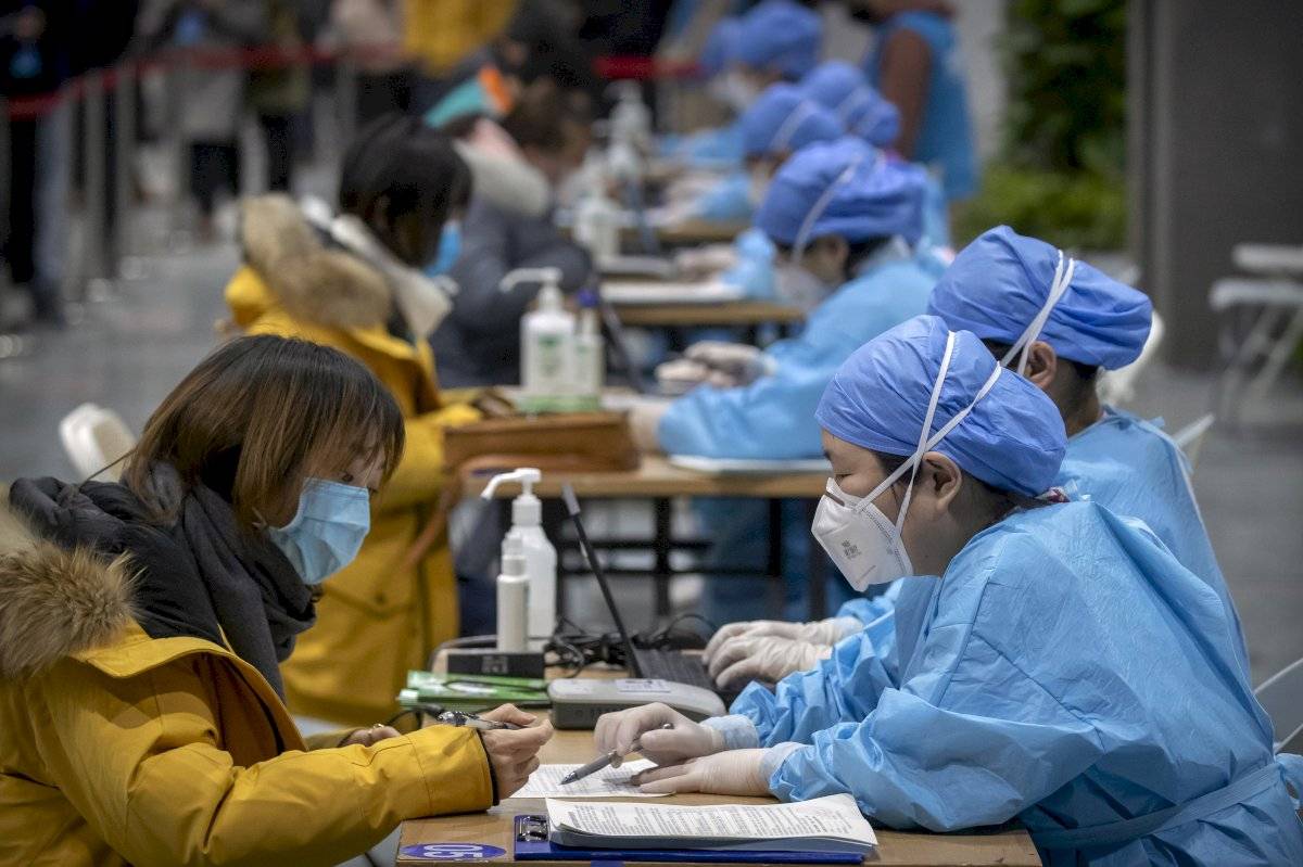 Un trabajador con ropa protectora inscribe a un paciente en un centro para vacunas contra el coronavirus en Beijing