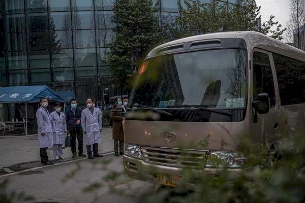 Los trabajadores médicos chinos se reúnen cuando los miembros de la OMS